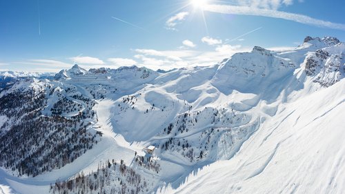 Enquire about your chalet holiday now! Sunny winter day in snow-covered mountains with ski trails and blue sky