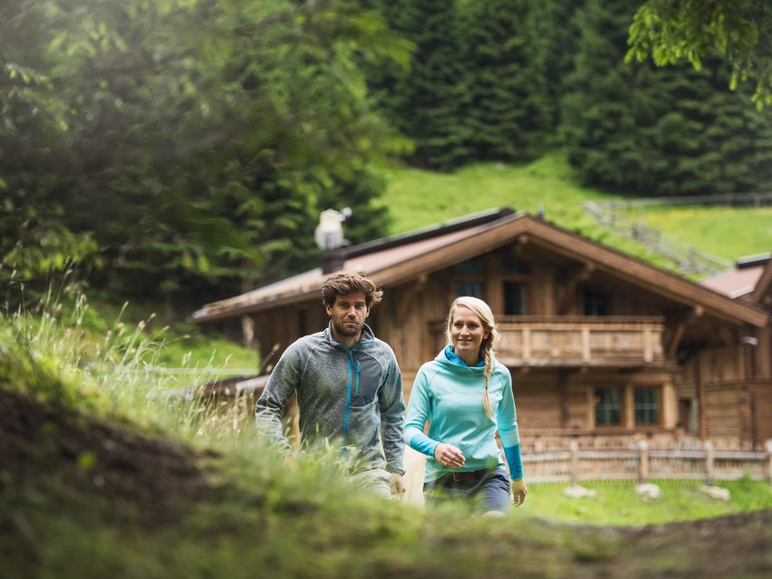 Ein unvergesslicher Sommerurlaub im Stubaital Paar wandert vor einer Berghütte im Grünen