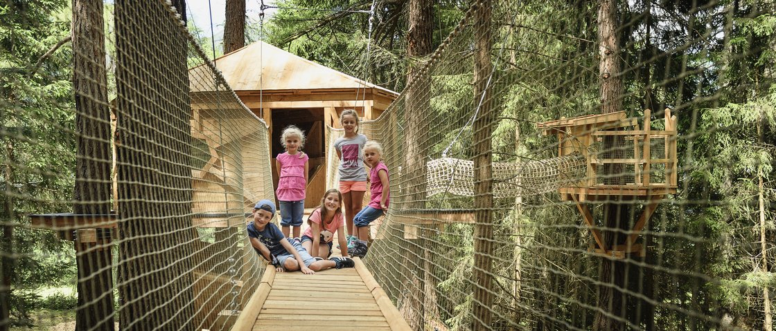 Stubaital, öffne dich! Kinder sitzen auf einer Hängebrücke in einem Waldabenteuerpark