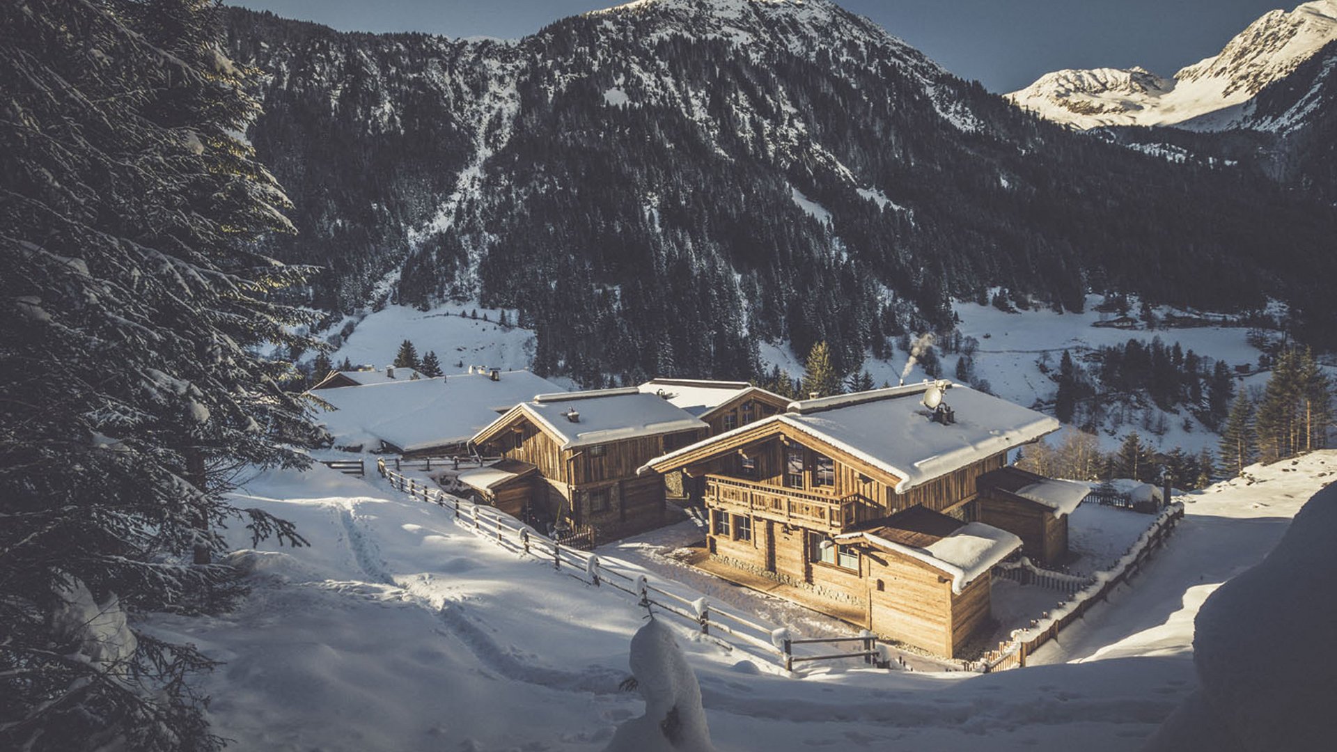 Wooden houses in snowy mountain landscape with pine trees and mountains