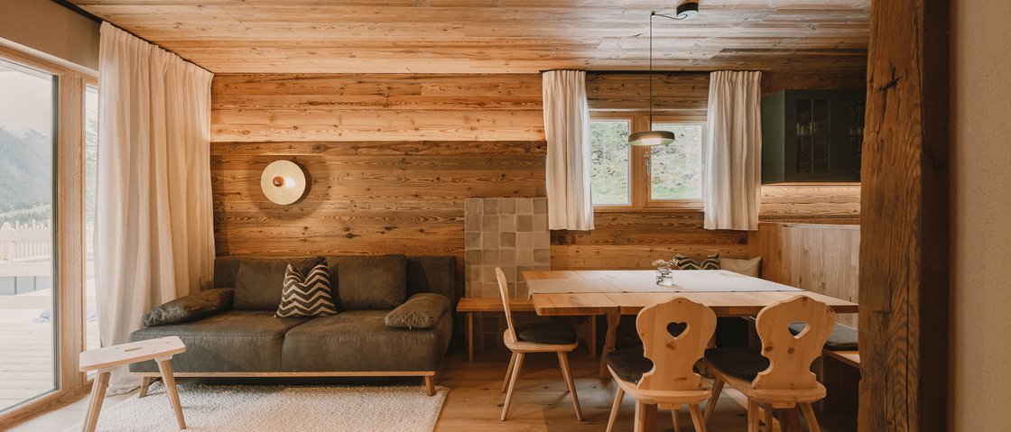 Get away from it all and relax at our chalet in Stubaital Cozy living room with wooden paneling, sofa, and dining table with chairs