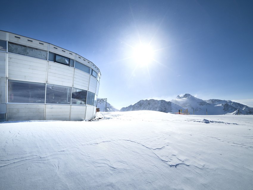 Highlights im Chalet in den Bergen Schneebedecktes Bergplateau mit Sonnenschein und Gebäude links