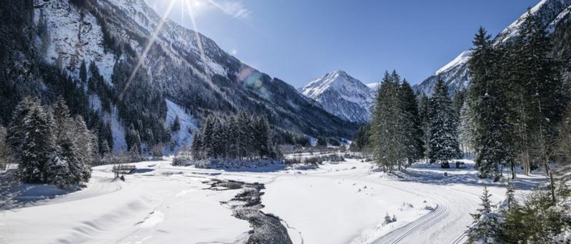 Warum Urlaub im Gletscher Chalet im Stubaital? Verschneites Tal mit Fluss, Bergen und strahlendem Sonnenschein