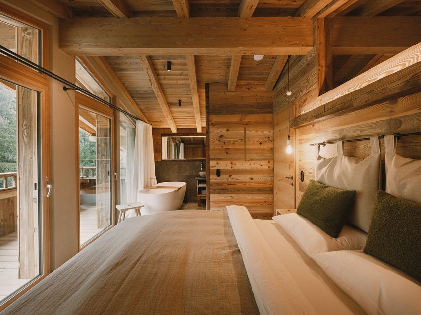 Get away from it all and relax at our chalet in Stubaital Cozy bedroom with wooden walls, bed, and freestanding bathtub