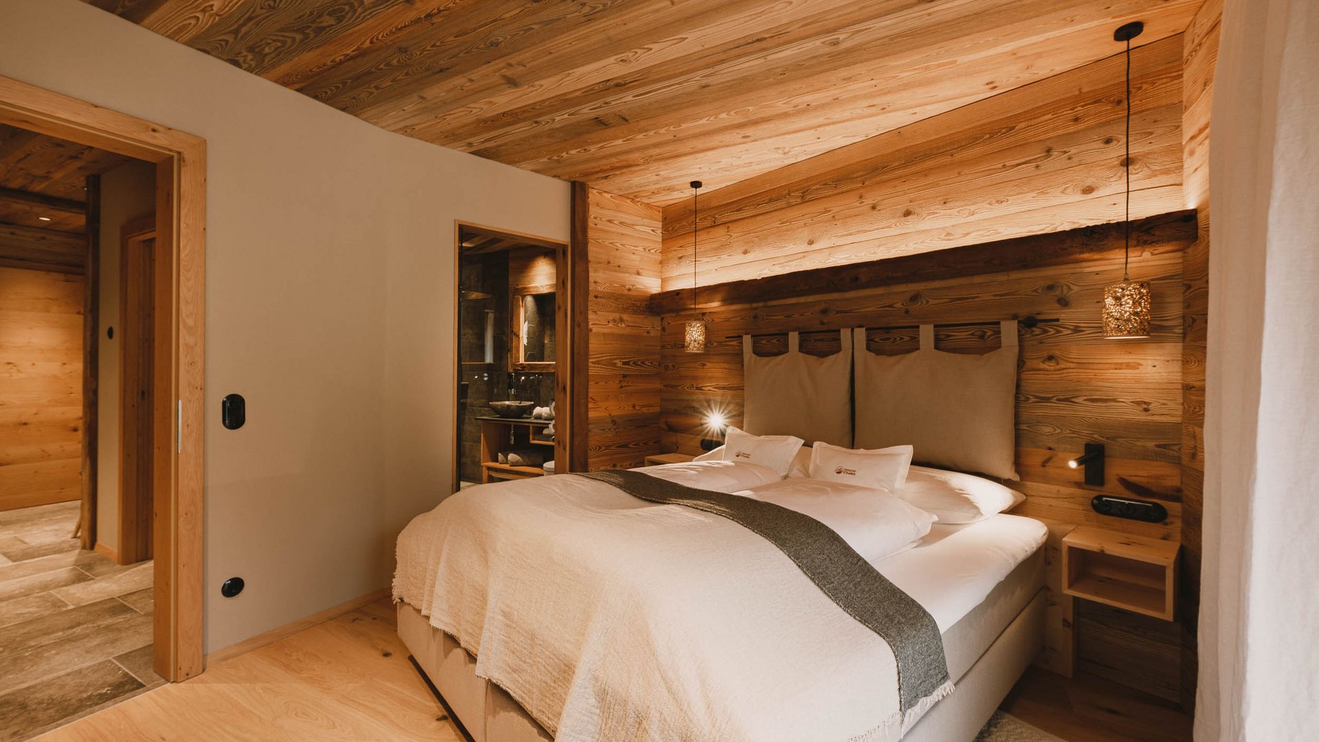 Get away from it all and relax at our chalet in Stubaital Cozy bedroom with wooden walls and large bed under warm lighting