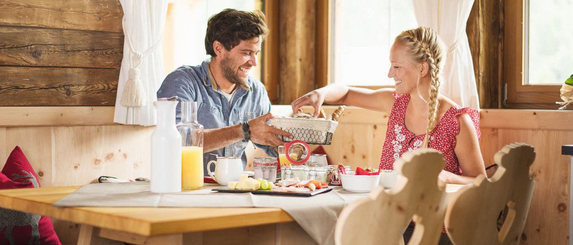 Warum Urlaub im Gletscher Chalet im Stubaital? Paar genießt Frühstück in gemütlicher Holzhütte mit natürlichem Licht