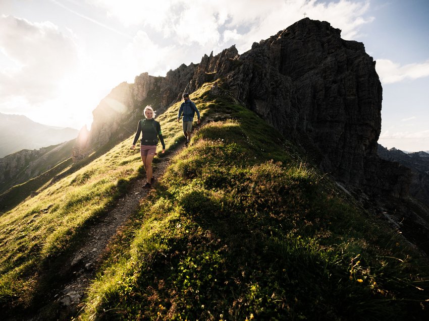 Highlights at your chalet in the mountains Two hikers walking on a mountain trail in sunlight