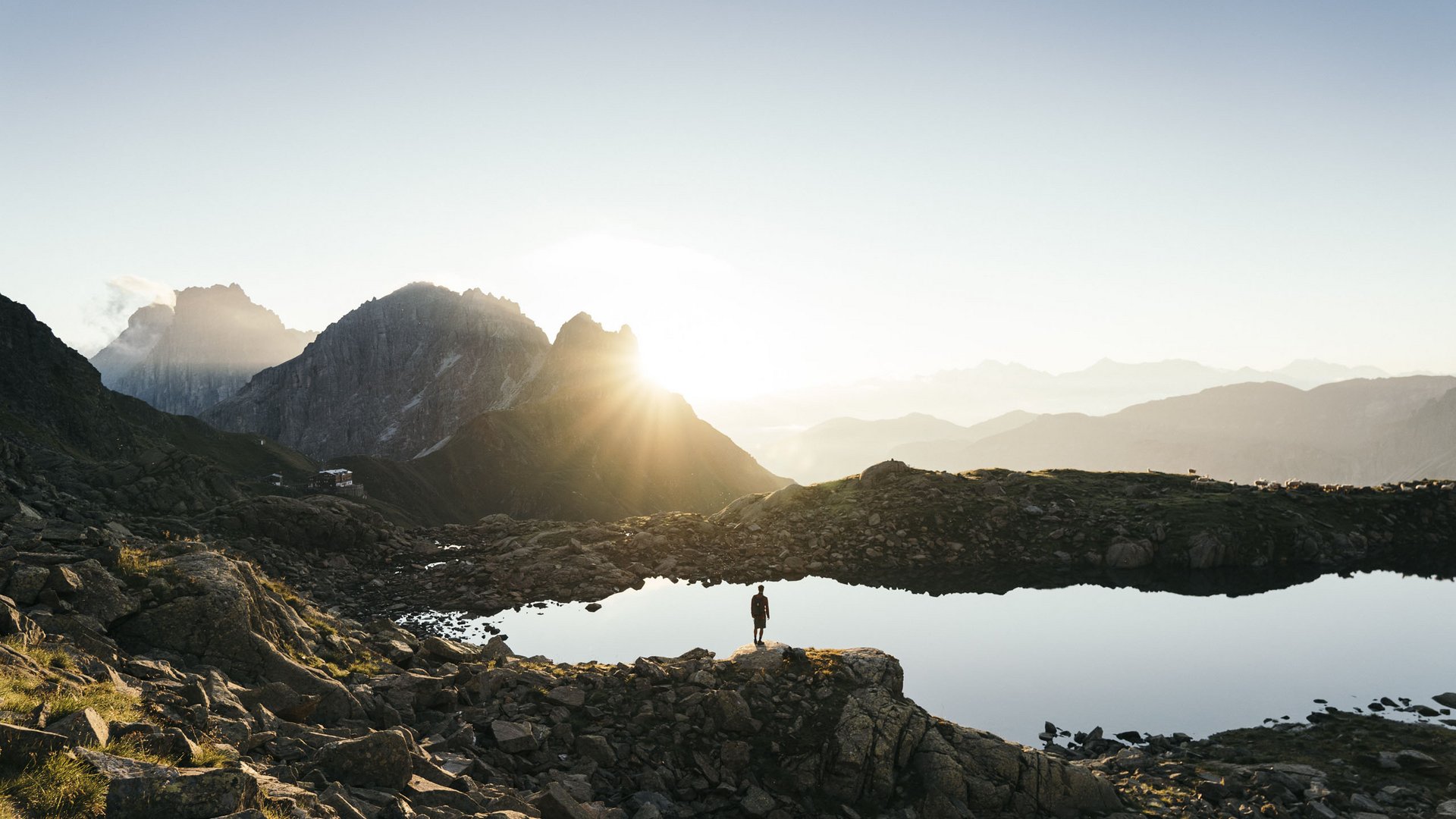 Highlights im Chalet in den Bergen Person steht auf Felsen am See in den Bergen bei Sonnenaufgang